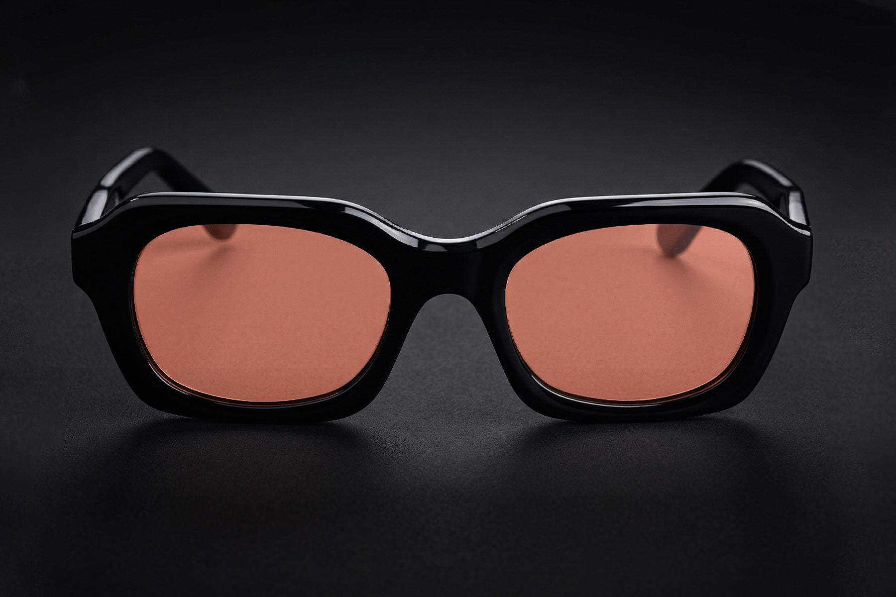 AARKA Andes C2 polarized irregular sunglasses featuring a black and orange full-rim frame with tinted lenses, shown in a front view.